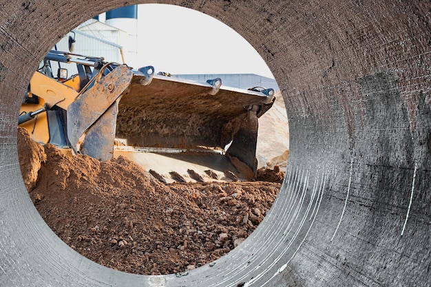El cargador de la excavadora trabaja con un cucharón para transportar arena en un sitio de construcción Equipo de construcción profesional para movimiento de tierras