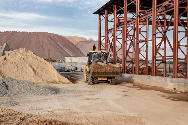 El cargador de excavadoras trabaja con un balde para transportar arena en un sitio de construcción. Equipo de construcción profesional para movimiento de tierras.