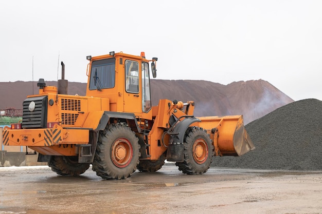 El cargador frontal recoge grava o piedra triturada en el cucharón delantero Maquinaria de construcción pesada en el sitio de construcción Transporte de materiales en una planta de hormigón