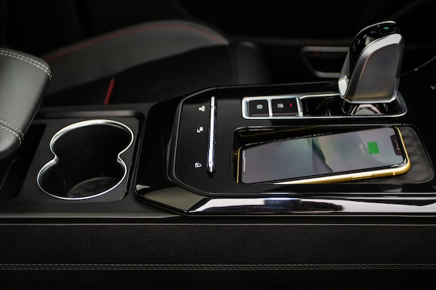 Cargador de móvil inalámbrico en el coche moderno. Cargador de coche inalámbrico portátil para smartphone. Carga del teléfono con cargador inalámbrico.