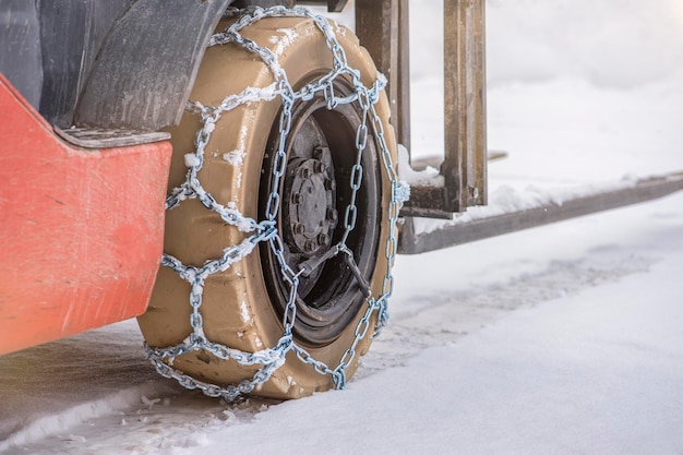 Cargadora de carga en invierno sobre nieve La cargadora se desplaza sobre nieve con cadenas en las ruedas para reducir el deslizamiento y el giro Seguridad de conducción en condiciones invernales