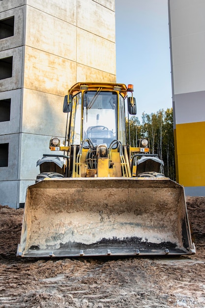 Cargadora de ruedas pesadas con un cucharón en un sitio de construcción. Equipos para movimiento de tierras, transporte y carga de materiales a granel: tierra, arena, piedra triturada.