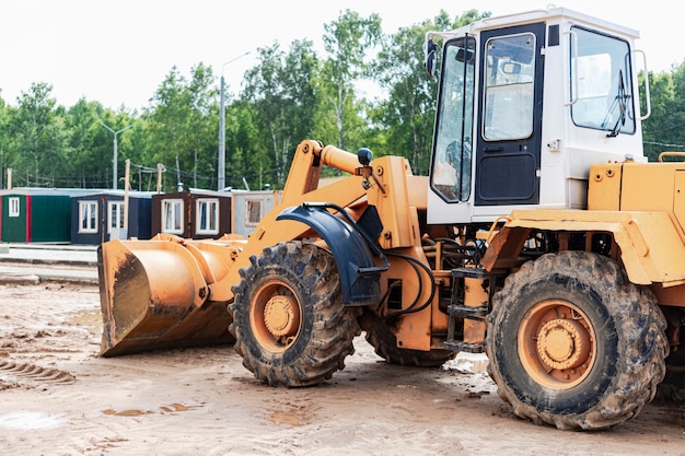 Cargadora de ruedas pesadas con un cucharón en un sitio de construcción. Equipos para movimiento de tierras, transporte y carga de materiales a granel: tierra, arena, piedra triturada.