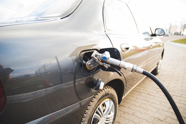 Cargue combustible con gasolina. Cerrar pistola de reabastecimiento de combustible en el cuello del tanque