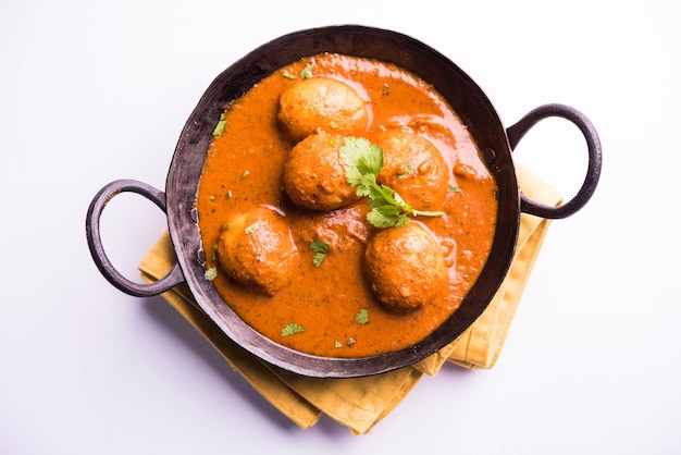 Caril de batata picante recém cozido na frigideira ou dum aloo quente e picante servido com tandoori roti ou naan ou pão indiano ou chapati e salada verde, foco seletivo