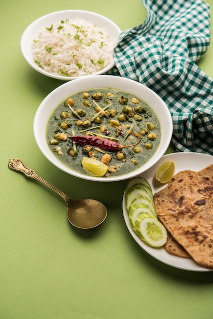 Caril de espinafre de grão de bico ou chana masala com palak servido com arroz e pão achatado ou paratha, foco seletivo