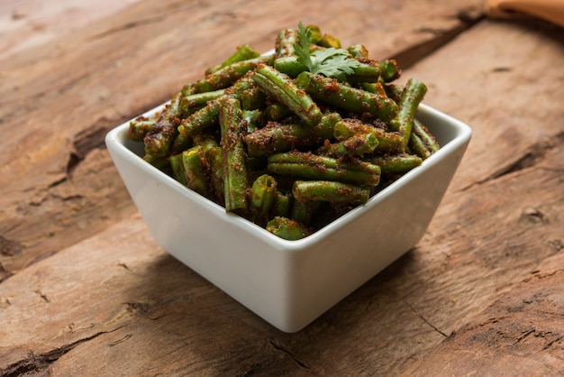 Caril de feijão verde Masala, receita de vegetais indianos servidos em uma tigela quadrada sobre um fundo colorido, foco seletivo