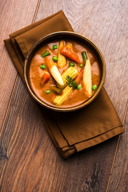 Caril de indian baby corn masala preparado em molho vermelho servido com roti / naan ou pão indiano. sobre fundo temperamental. foco seletivo