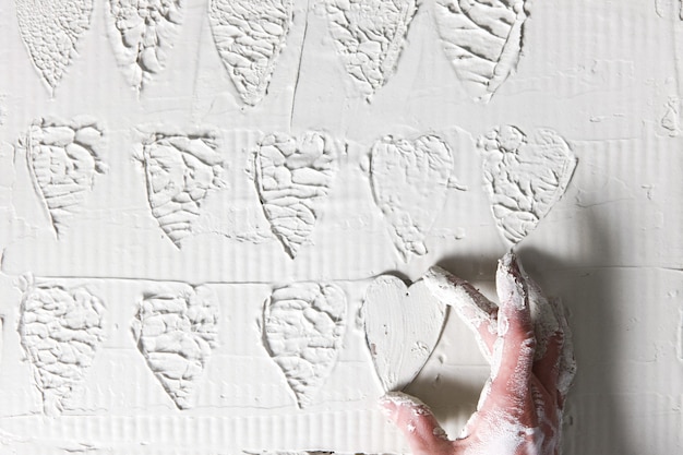 Carimbo de coração de mão Fundo de gesso branco decorativo padrão de estuque conceito de amor feito à mão