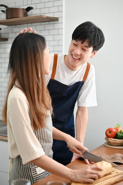 Carinhoso e adorável jovem namorado asiático tendo um momento romântico com sua namorada na cozinha