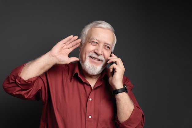 Carismático homem grisalho de camisa vermelha, rindo e falando ao telefone