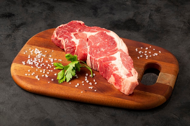 Carne de ancho cruda lista para asar sobre una tabla de cortar de madera