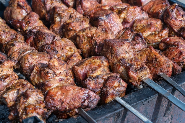 Carne asada cocinada a la parrilla. Brocheta a la plancha para cocinar en una brocheta de metal. BBQ rebanadas de chuleta de carne de res fresca. Plato tradicional oriental, shish kebab. Parrilla de carbón y llama, comida callejera, Ucrania