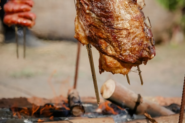 Carne asada y cortada en mesa y fogata con leña estilo gaucho