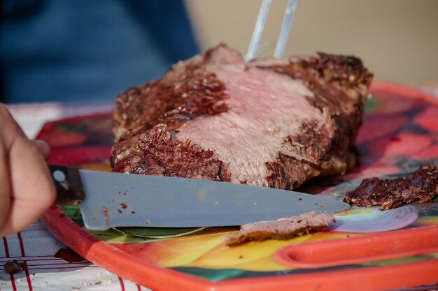 Carne asada y cortada en mesa y fogata con leña estilo gaucho