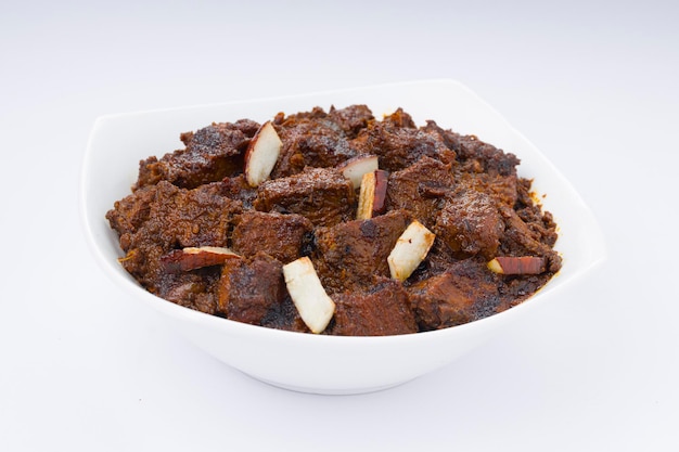 Carne asada masala o receta casera de curry dispuesta en tazón blanco con fondo blanco