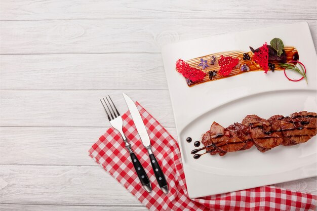 Carne asada con piña en salsa balsámica sobre una tabla de madera blanca