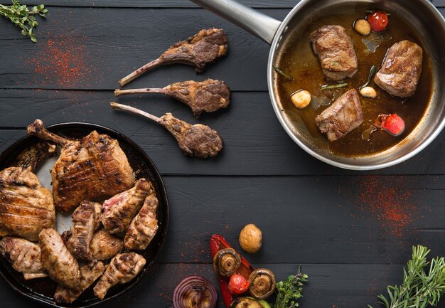 Carne asada en una sartén sobre un fondo de madera negra