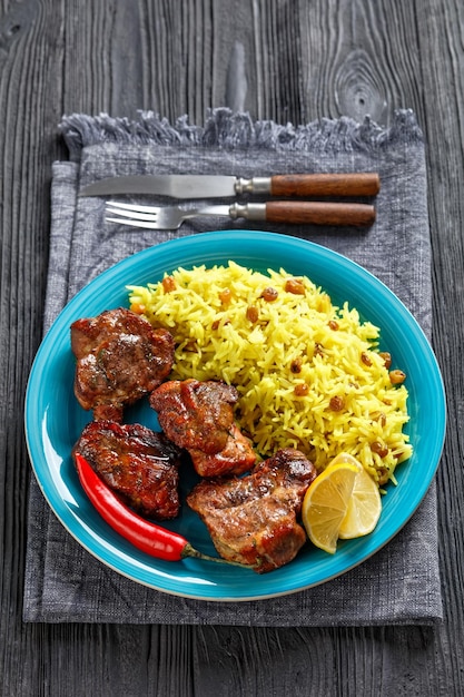 Carne asada servida con arroz con pasas y azafrán