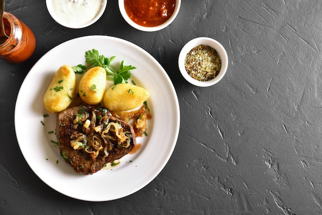 Carne assada com batata na chapa branca sobre fundo de pedra preta com espaço de cópia Vista superior plana