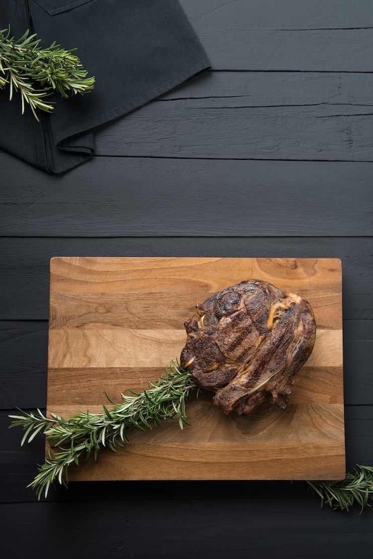Foto carne assada com verduras em uma tábua de cortar em um fundo preto de madeira