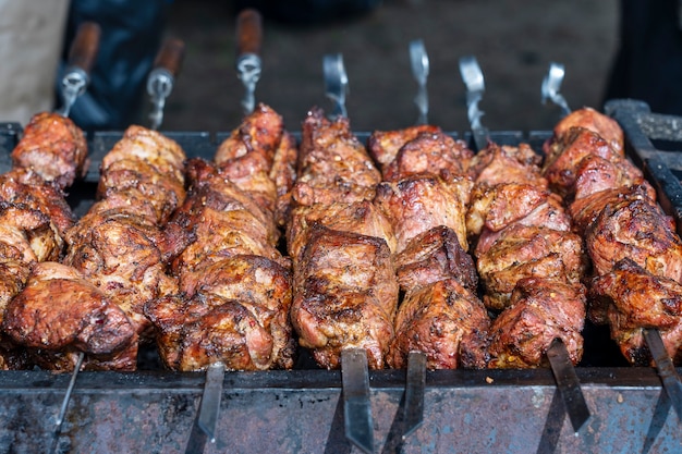 Carne assada cozida no churrasco. espetada grelhada cozinhando no espeto de metal. fatias de costeleta de carne bovina fresca de churrasco. prato oriental tradicional, shish kebab. grelhados a carvão e fogo, comida de rua, ucrânia