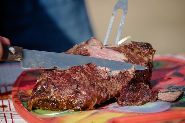 Carne assada e cortada na mesa e fogueira com lenha gaúcha