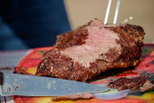 Carne assada e cortada na mesa e fogueira com lenha gaúcha