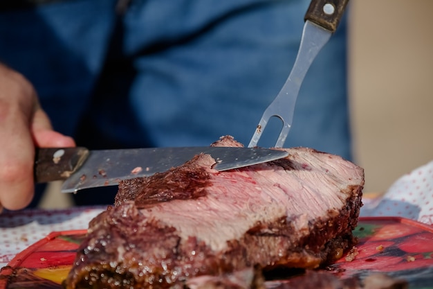 Foto carne assada e cortada na mesa e fogueira com lenha gaúcha