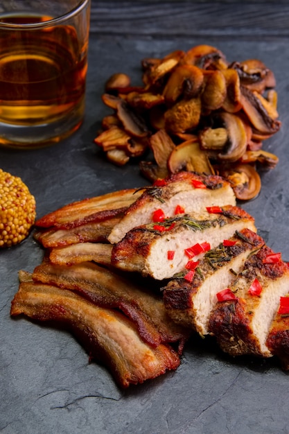 Carne assada servida com cogumelos fritos e fatia de bacon
