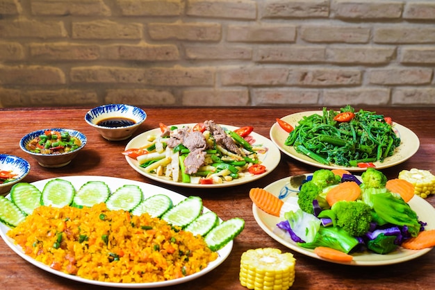 Carne assada vietnamita com mamão, arroz frito com carne de porco, salada e molhos na mesa de madeira