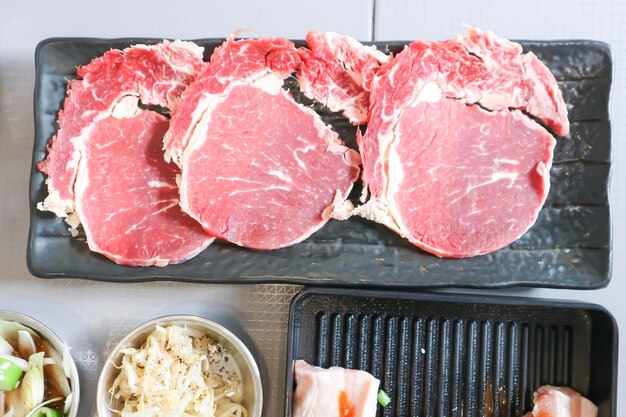 Foto carne bovina crua em fatias ou carne bovina para cozinhar e salada coreana