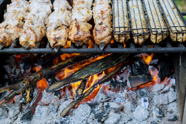 La carne en brochetas de metal se asa a la parrilla con carbón vegetal.