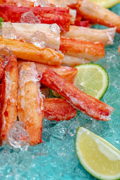 carne de cangrejo y partes del cuerpo, tentáculos, cubos de rodilla, fondo marino azul sobre hielo, rodajas de limón y