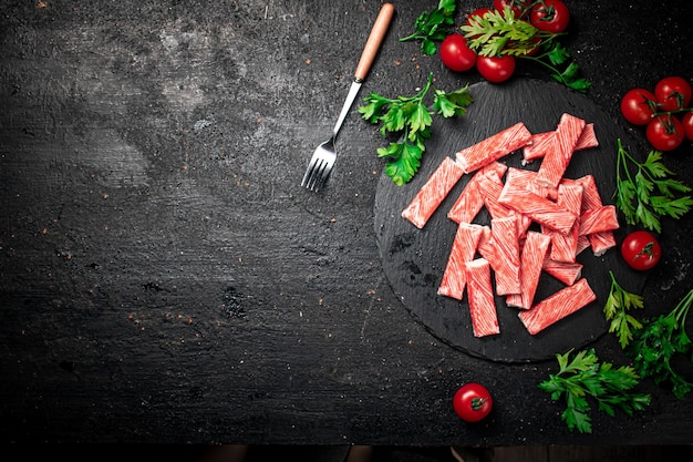 Carne de cangrejo en una placa de piedra con tomates frescos y hierbas