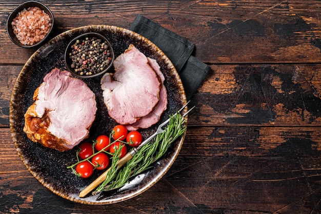 Carne de cerdo ahumada - gammon con hierbas en plato rústico. Fondo de madera. Vista superior. Copie el espacio.