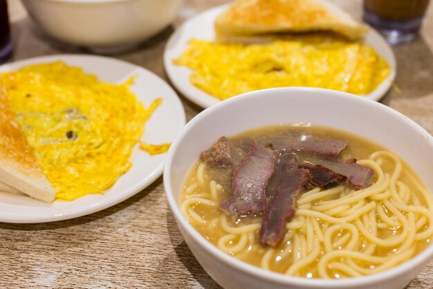 Foto carne de cerdo asada con sopa de pasta y tostadas en un restaurante al estilo de hong kong