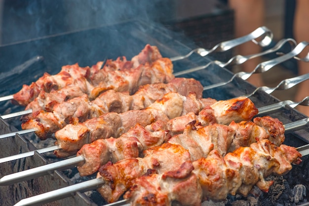 Carne de cerdo a la brasa en brochetas de metal cocción barbacoa el humo de las brasas se desarrolla sobre la carne ...