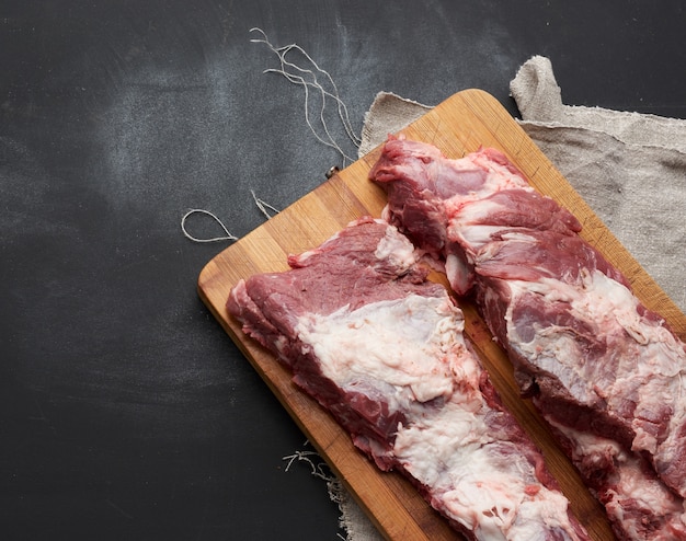 Carne de cerdo en costillas con capas de grasa sobre una tabla para cortar madera