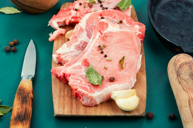 Carne de cerdo cruda con condimentos en una tabla de madera Entrecote