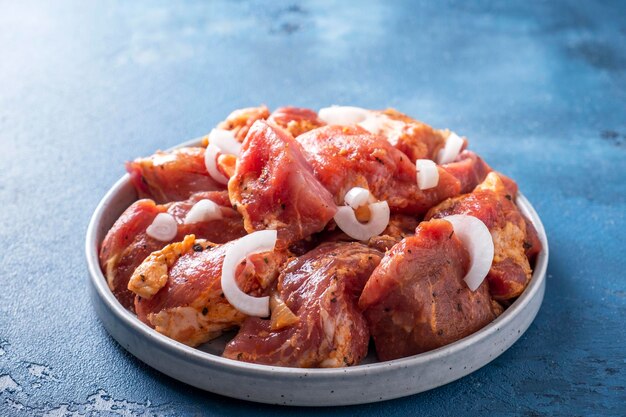 Carne de cerdo cruda con especias y cebolla Sashlik marinado en un plato listo para cocinar