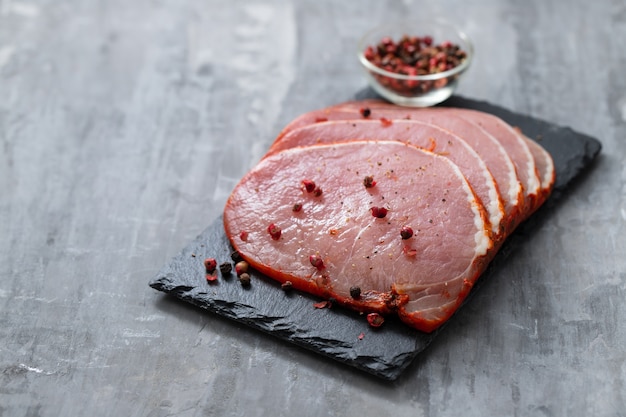 Carne de cerdo cruda con pimienta sobre placa de cerámica negra