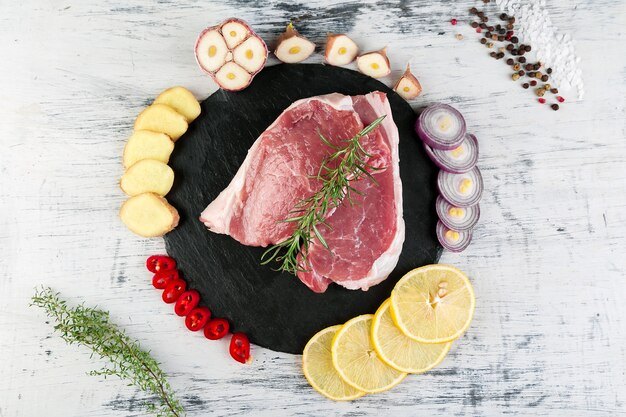 Carne de cerdo cruda en placa de pizarra negra con ingrediente de especias