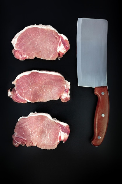 Carne de cerdo cruda en rodajas con cuchillo de carne sobre fondo oscuro