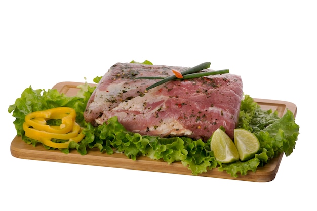 Carne de cerdo cruda en tabla de cortar sobre fondo blanco.