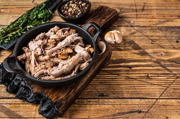 Carne de cerdo desmenuzada desmenuzada lentamente en una sartén con cuchillo de carnicero. de madera