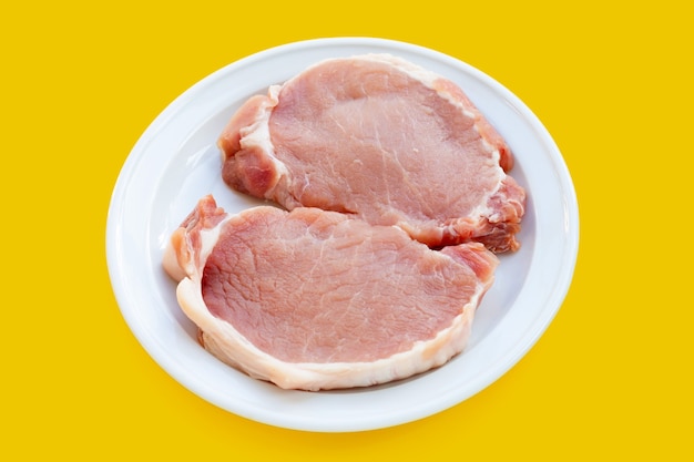 Carne de cerdo fresca en plato blanco sobre fondo blanco.