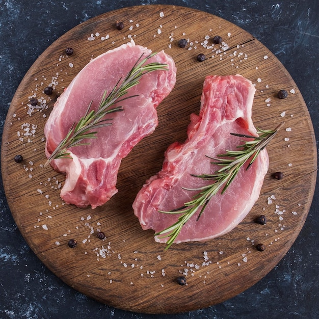 Carne de cerdo fresca en una tabla de madera con romero Vista superior