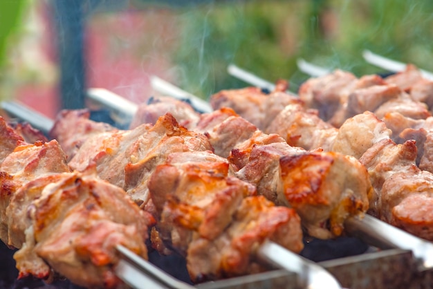 Carne de cerdo a la plancha en pinchos de metal. Cocinar a la parrilla. El humo de las brasas se desarrolla sobre la carne. Banner promocional para menú con espacio de copia para insertar texto.