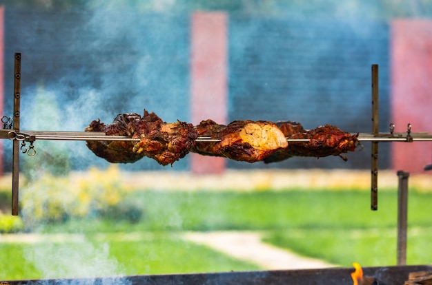 La carne del cerdo se prepara en un pincho en el fuego en el patio en el verano. El humo da picor a la carne.